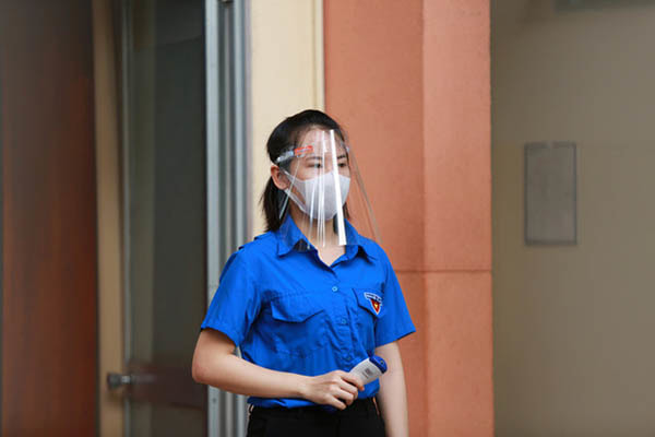 Cán bộ Đoàn trường được trang bị nón chống giọt bắn khi đo thân nhiệt cho học sinh.